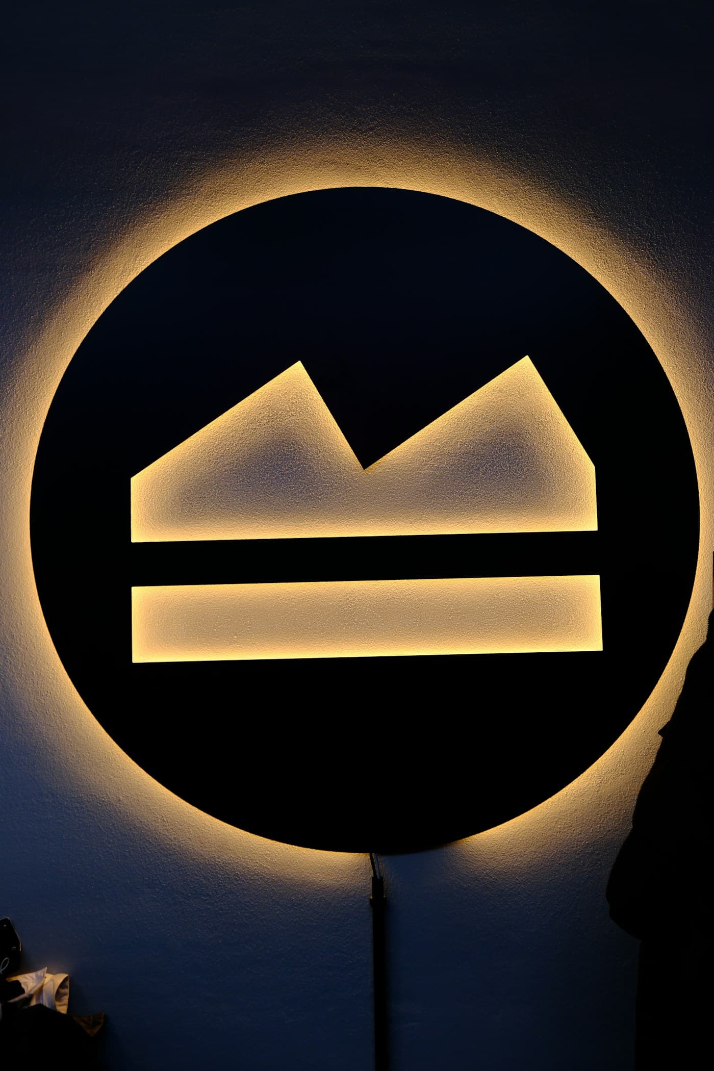 Koyu bir duvarda arkadan aydınlatılmış yuvarlak logo tabelası