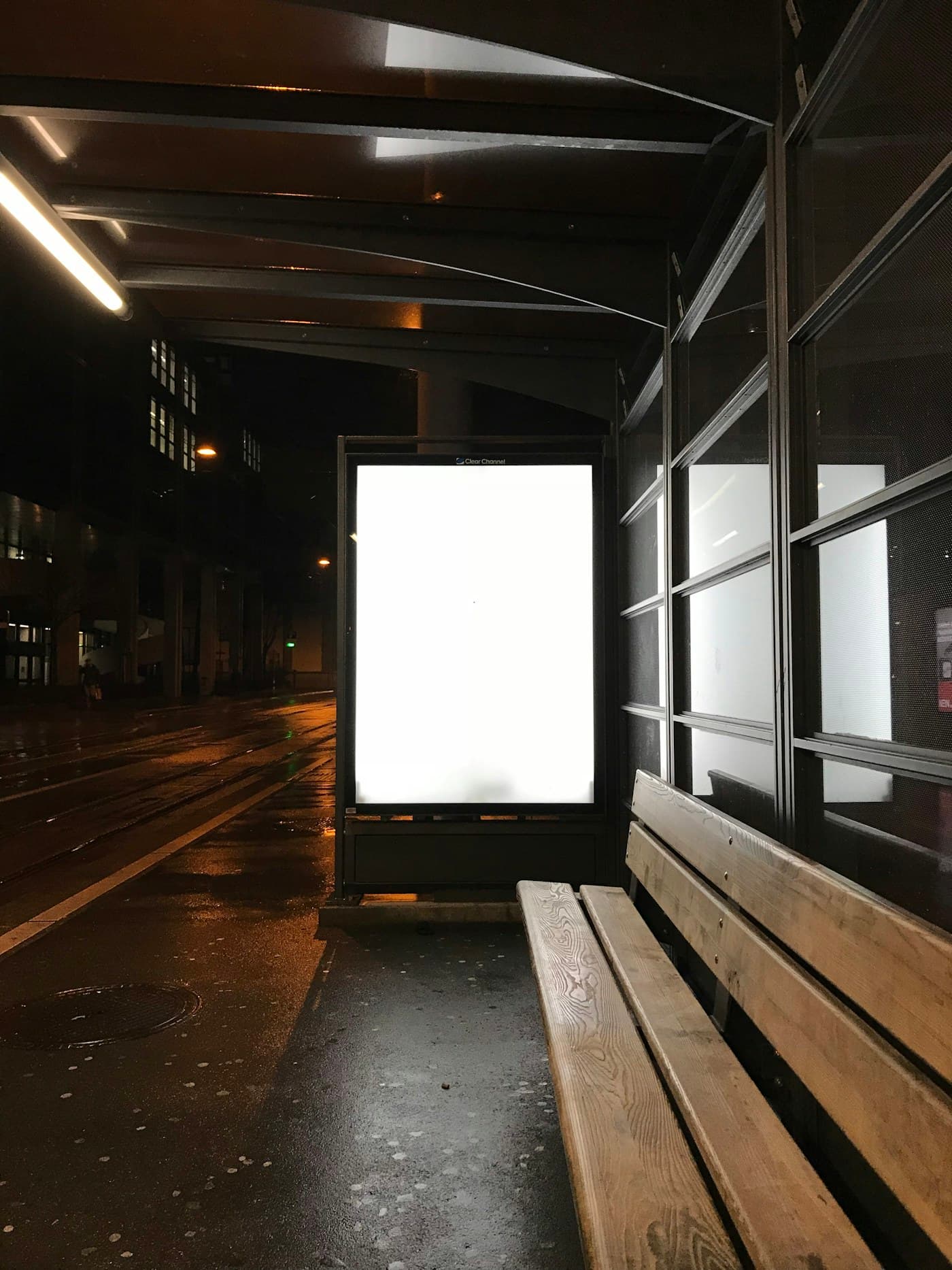 Yağmurlu bir gecede otobüs durağında ışıklı, boş reklam panosu