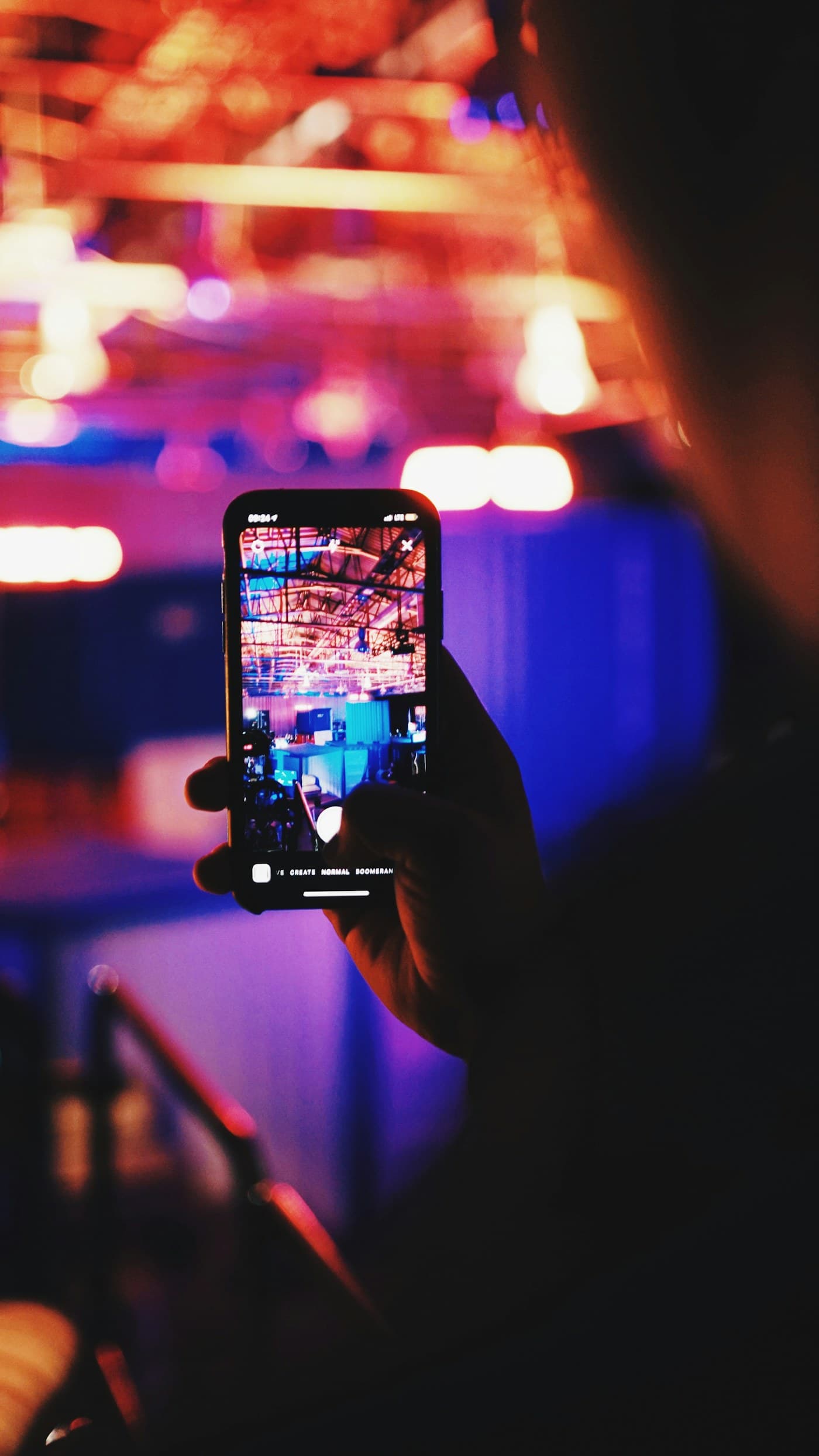 Renkli ışıklar altında bir etkinliği telefonla çeken el