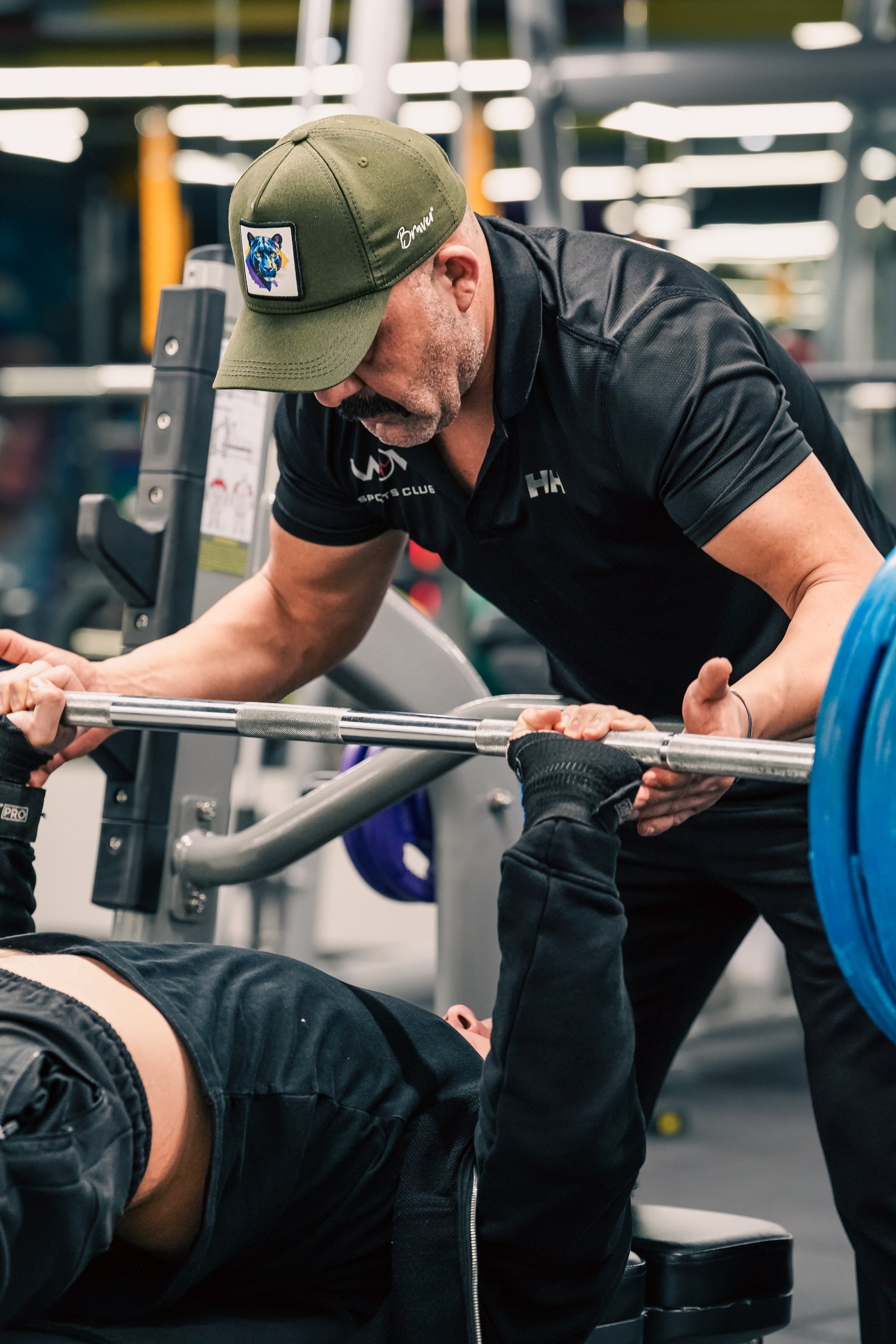 Spor salonunda bench press yapan üyeye eşlik eden antrenör